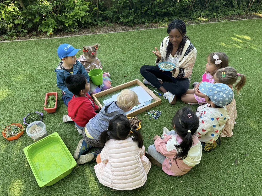 children-garden-activity-1000px Children and their teacher explore leaves and plants together during an outdoor learning activity in the kindergarten garden